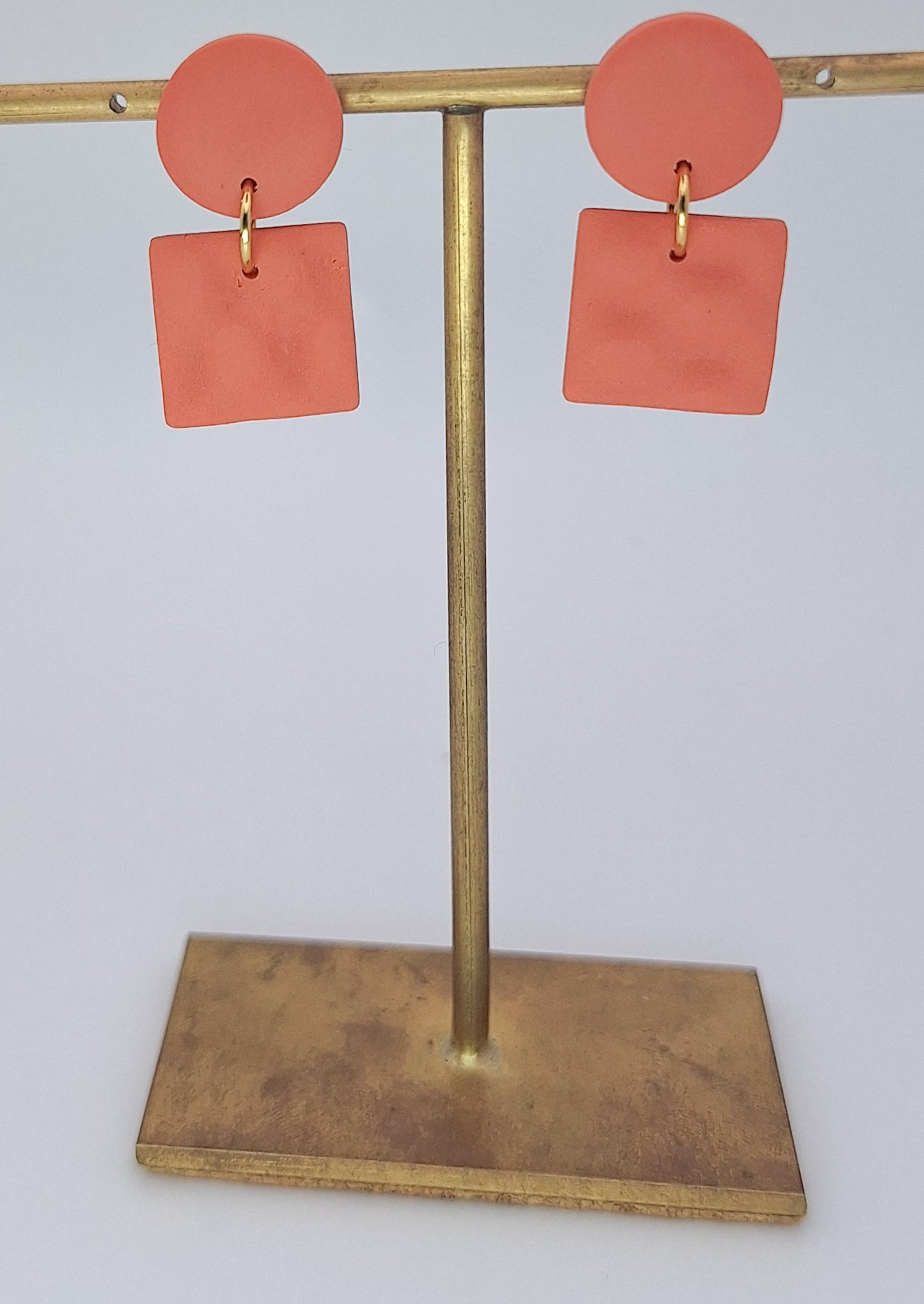Coral earrings on a gold earring stand against a white background