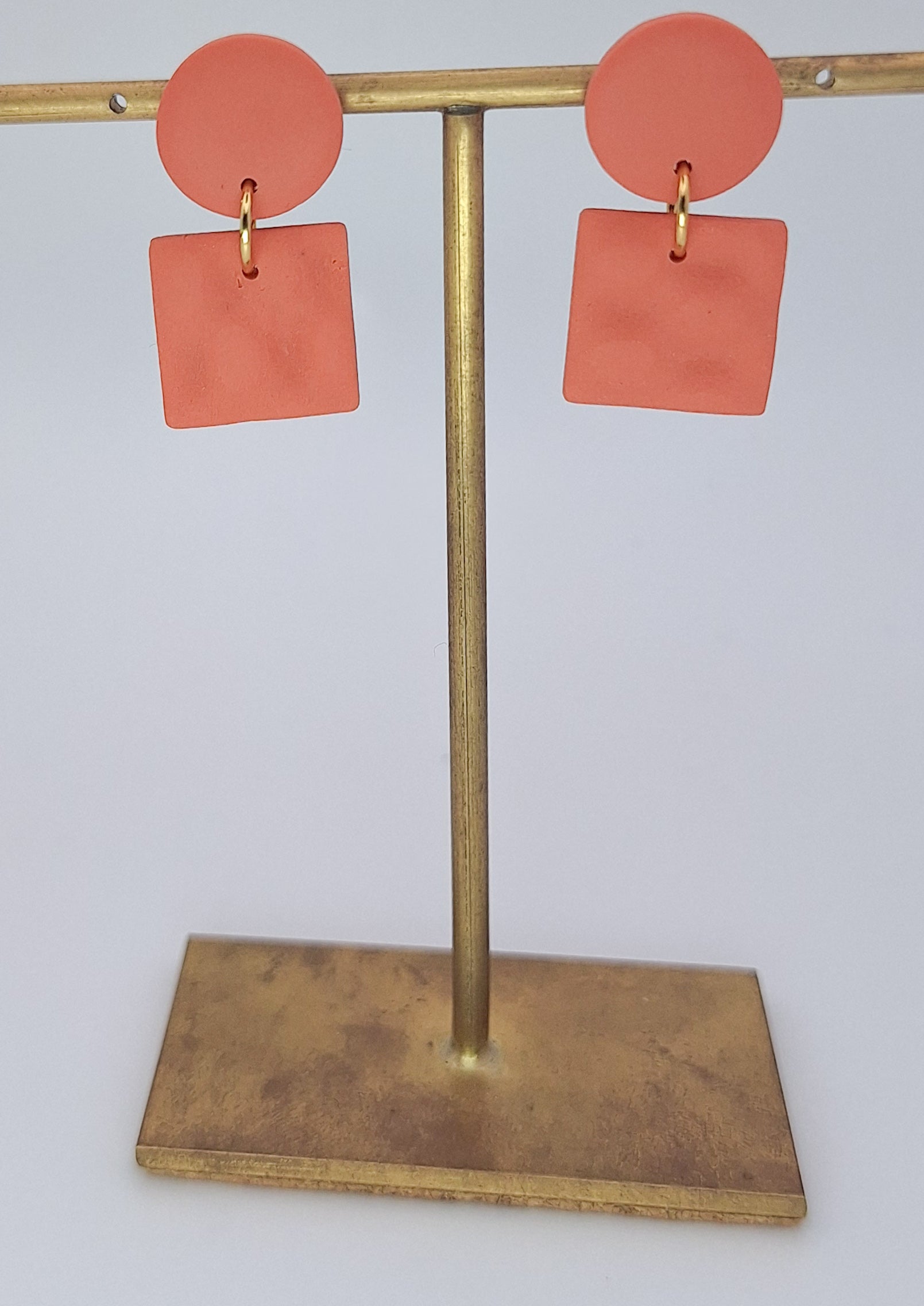 Coral earrings on a gold earring stand against a white background
