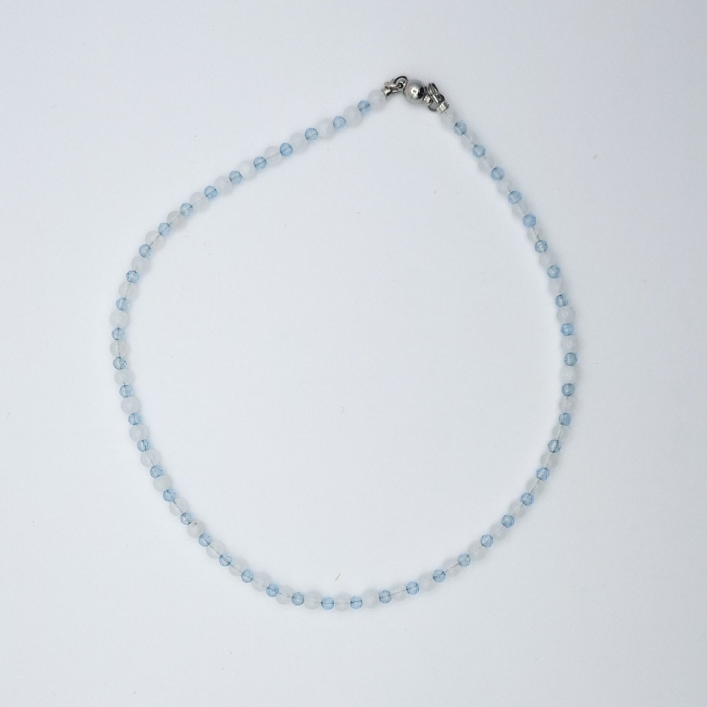 Necklace with small blue beads and a silver clasp on a light gray background
