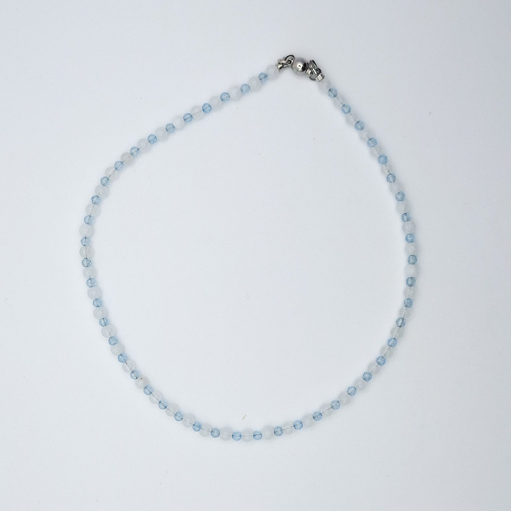 Necklace with small blue beads and a silver clasp on a light gray background
