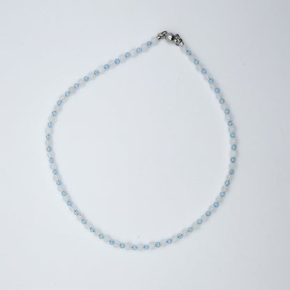 Necklace with small blue beads and a silver clasp on a light gray background
